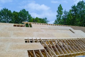 An under construction wooden home is being constructed on roof plywood construction site
